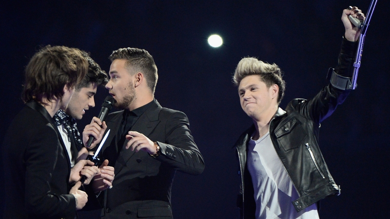 Niall Horan raises a crutch to the crowd at last night's Brit Awards while on stage with his One Direction band members