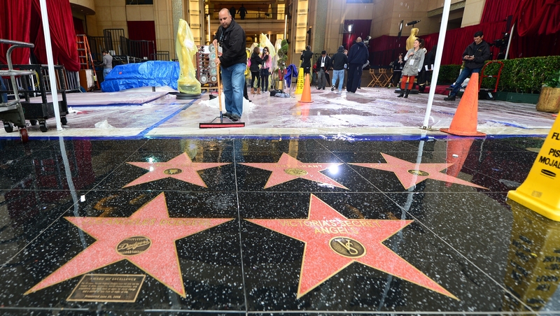 Water from heavy rain is swept off the floor in front of the Dolby Theatre in Hollywood