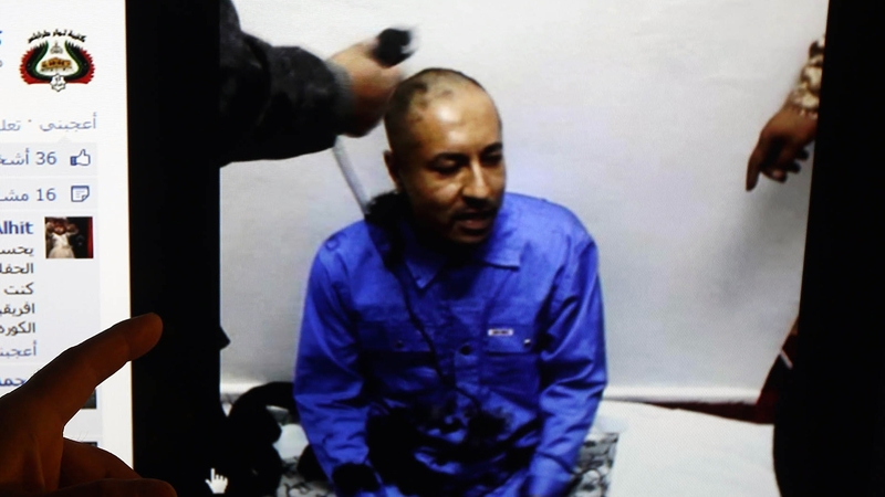 A man shows a screen with a picture of Saadi Gaddafi, which was released on the Facebook page of Tripoli Revolutionaries Brigade