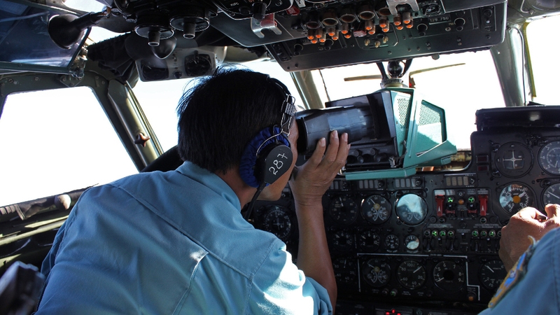Military personnel scan the sea aboard a Vietnamese Air Force aircraft in the search for flight MH370