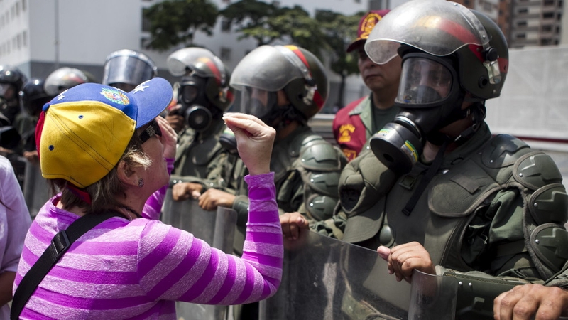 A woman protests in front of members of the Bolivarian National Guard during a demonstration in Caracas (Pic: EPA)