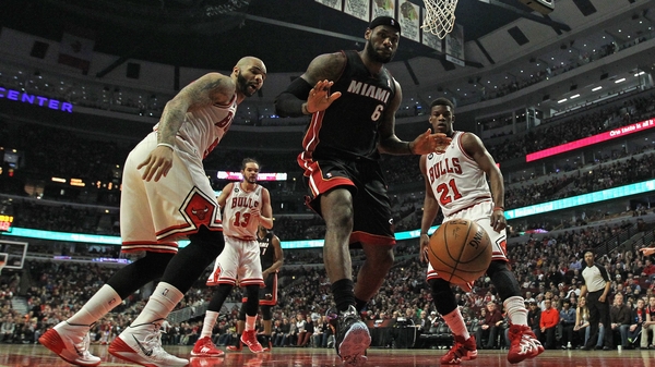 Carlos Boozer (l) and Jimmy Butler of the Chicago Bulls watch as LeBron James of the Miami Heat looses the ball out of bounds
