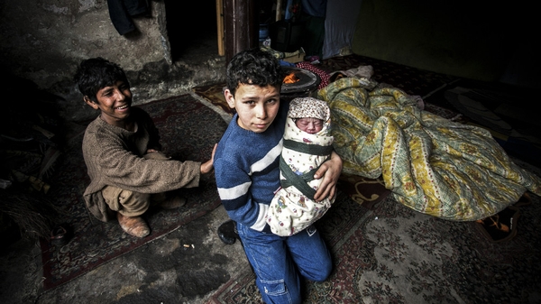 A Syrian refugee boy poses with his newborn brother as their mother lies near them in a house in the Basaksehir district of Istanbul