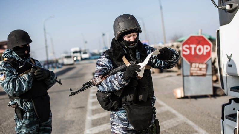 A pro-Russian serviceman checks a driver's documents at Chongar checkpoint blocking the entrance to Crimea
