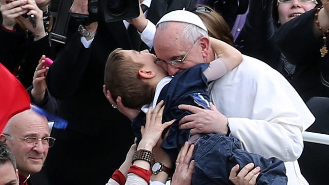 Pope Francis embraces a boy prior to his first 'Urbi et Orbi' blessing from the balcony of St Peter's