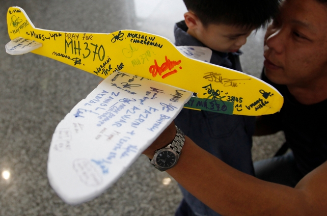 A man holds a model plane with well-wishing messages for the passengers of MH370 at Kuala Lumpur International Airport, Malaysia