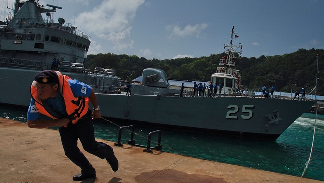 Members of the crew of the Malaysian Navy ship KD Kasturi prepare the ship during refueling and restocking at Kuantan Naval Base in Kuantan, Malaysia