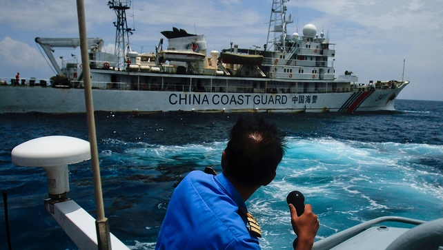 A member of the Malaysian Navy makes a call as their ship approaches a ship belonging to the Chinese Coast Guard during an exchange of communication in the South China Sea