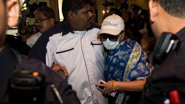 A family member of a missing relative is escorted from the news conference