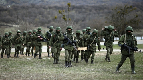 Russian military personnel move towards a Ukrainian military base in Perevalnoe