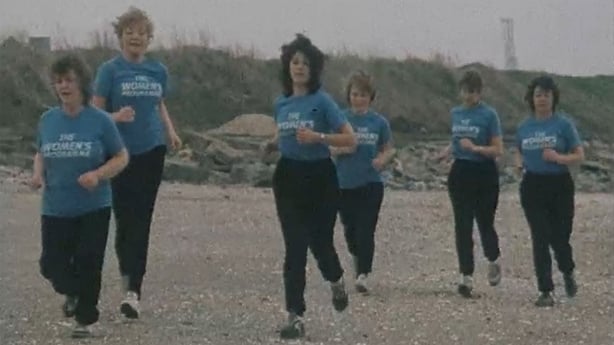 Journalists from The Women's Programme in matching blue t-shirts running on the beach