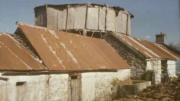 A large motorcycle wall of death looming up behind some cottages
