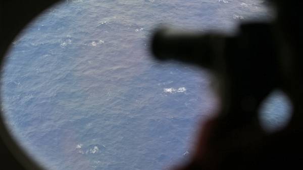 An observer on a Japan Coast Guard Gulfstream aircraft takes photos while searching Flight MH370