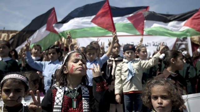 Palestinian children flash the 'V-sign' for victory and hold national flags during a demonstration demanding for the lifting of the Israeli blockade on the Gaza Strip and marking the Palestinian children's Day