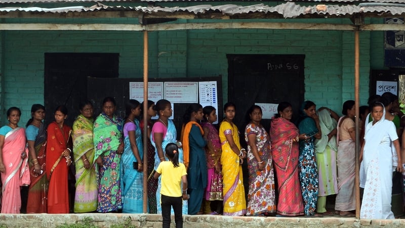 Voters wait in line outside a polling stating in Dibrugarh