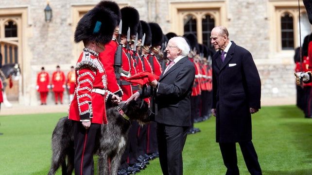 President Higgins presents a new ceremonial red coat to Domhnall of Shantamon, mascot of the Irish Guards