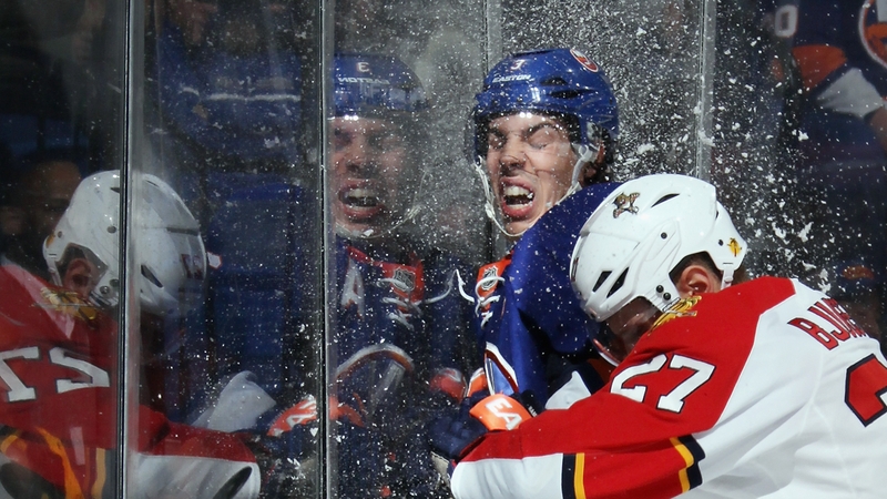Travis Hamonic of the New York Islanders ice hockey team takes a hit from Nick Bjugstad of the Florida Panthers