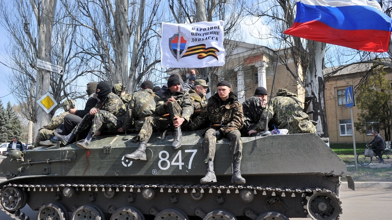 Men wearing military fatigues ride on an armoured personnel carrier in the eastern Ukrainian city of Slaviansk