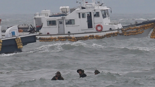 Divers fight against high waves as they struggle to search for hundreds of missing passengers