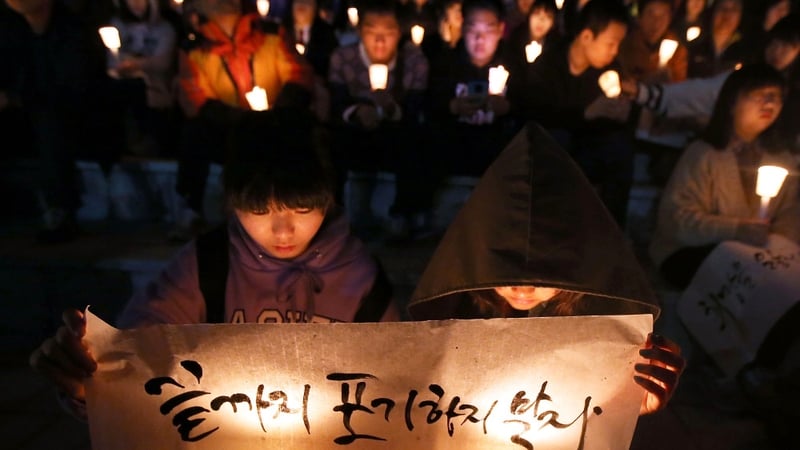 People hold candles as they pray for the safe return of passengers of the sunken ferry in Ansan, South Korea