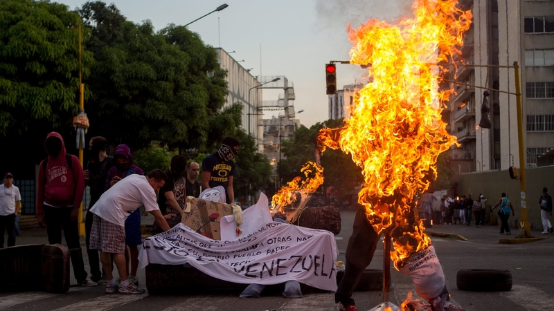 A figure with the image of President Nicolas Maduro is burned during the tradition of the Burning of Judas in Caracas, Venezuela