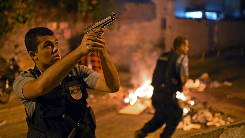 A Brazilian police special forces member takes position during a violent protest in a favela near Copacabana in Rio de Janeiro