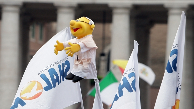 A pilgrim holds a puppet featuring Pope Francis