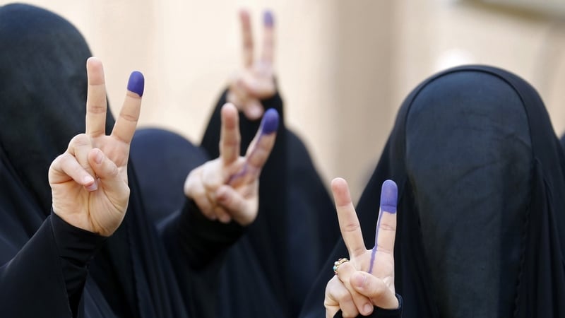 Iraqi women flash the sign for victory with their ink-stained fingers after casting their vote in Baghdad
