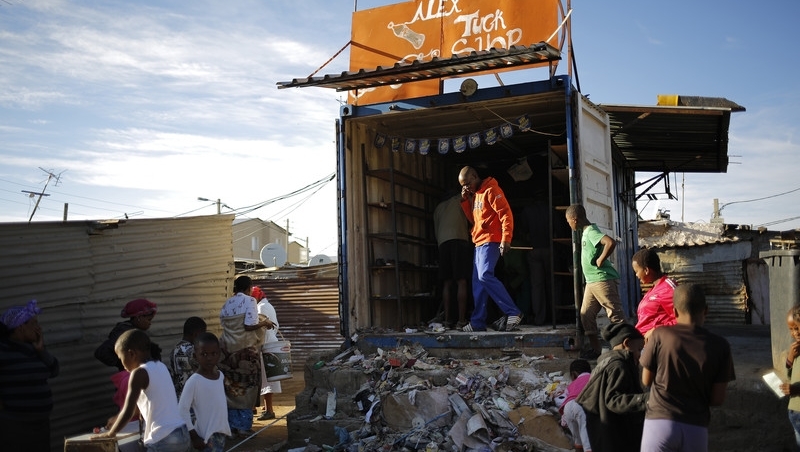 A shop owner cleans up after overnight violence in the Alexandra township