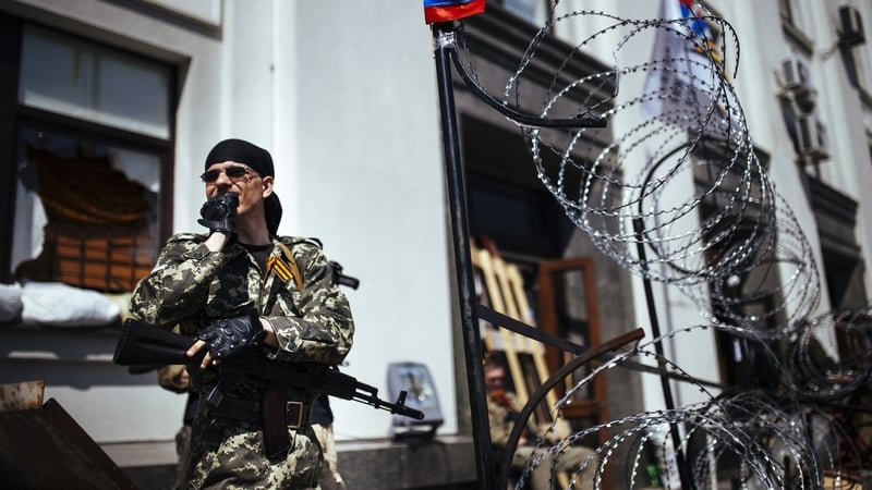 An armed pro-Russian activist stands guard outside a regional state administration building in the eastern Ukrainian city of Lugansk