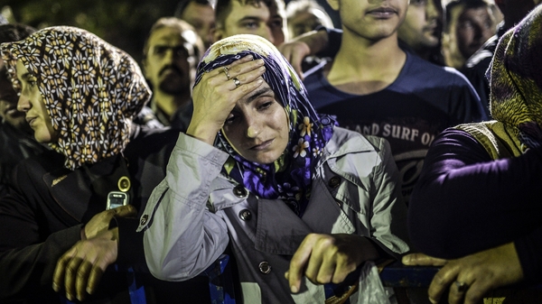 People stand in front of a hospital as they wait for news about their relatives