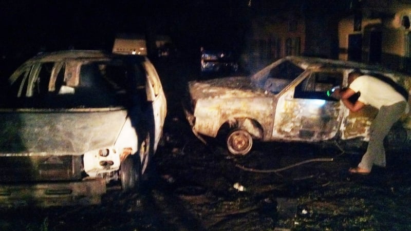 A man checks the wreckage of a car at the scene of the blast