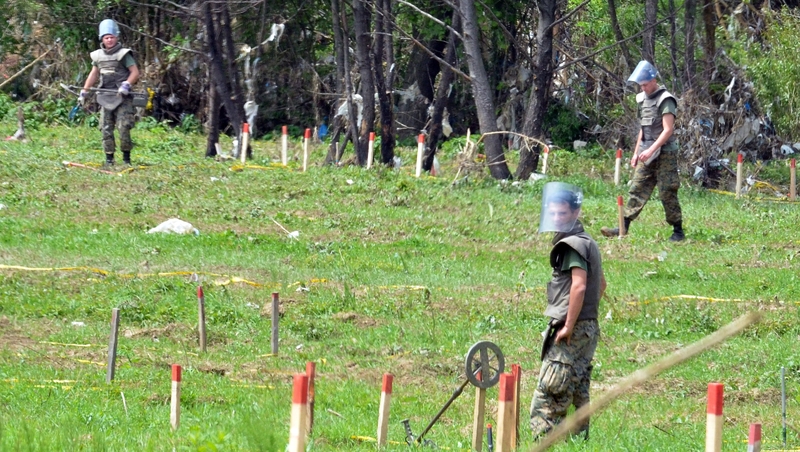 Mine clearance experts search a field after flood waters receded from the village of Cekrekcije, near Sarajevo