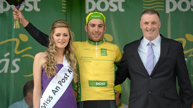 Patrick Bevin, New Zealand National Team, is presented with the An Post yellow jersey by Miss An Post Rás Charleville Laura Dundon and Edward Geaney, Delivery Services Manager