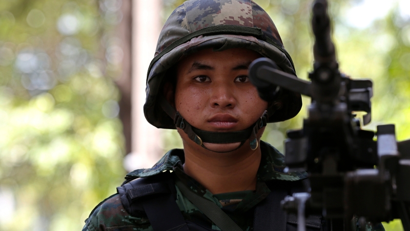 A Thai solider stands guard with a heavy machine gun
