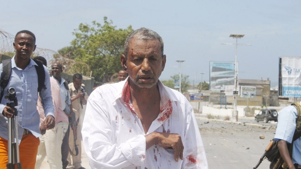 A wounded man walks by journalists following the attack