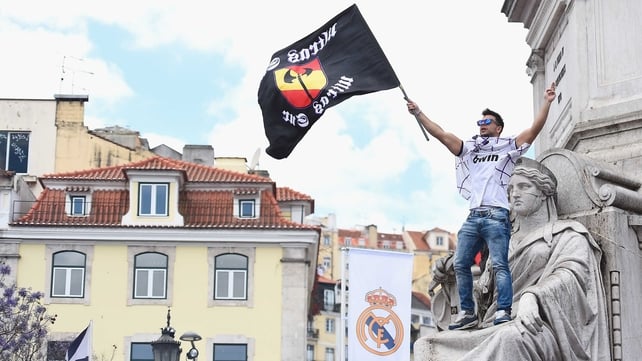 A Los Blancos fan is cradled by a statue in Lisbon