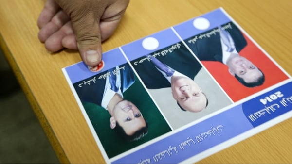 A Syrian man presses his thumb, a drop of blood on it, onto a ballot paper
