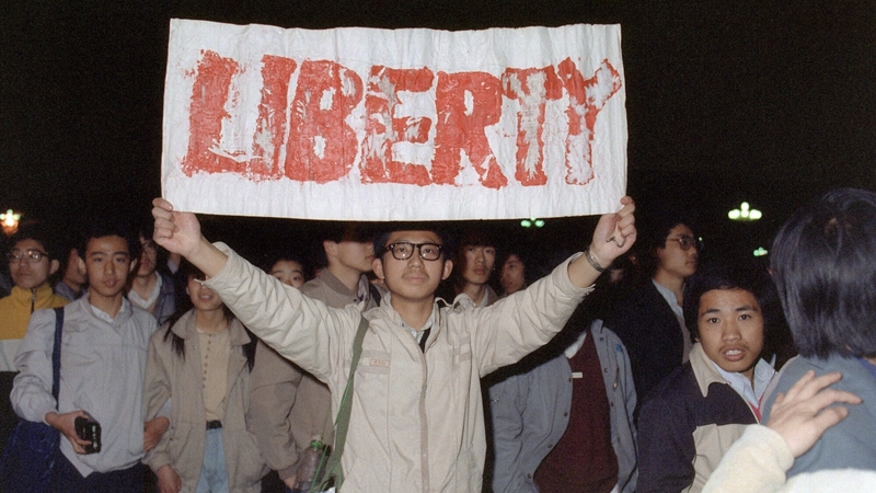A student displays a banner with one of the slogans chanted by the crowd of some 200,000 pouring into Tiananmen Square 22 April 1989
