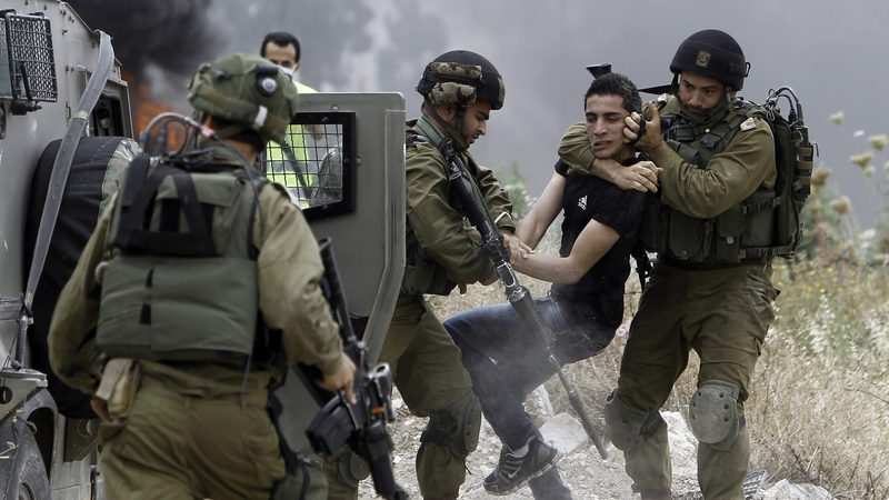 Israeli soldiers detain a Palestinian protester following a demonstration against the expropriation of Palestinian land by Israel
