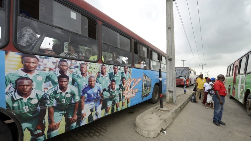 Commuters queue to board a bus in Lagos decorated with photographs showing ‘Super Eagles’ players