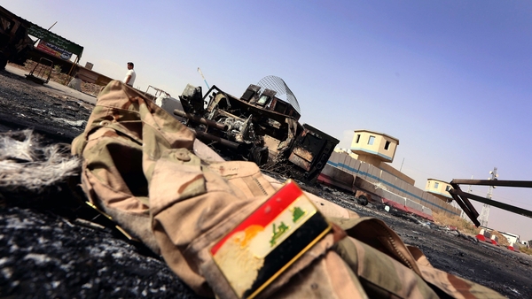 An Iraqi Army uniform lies on the ground in front of the remains of a burnt out Iraqi army vehicle east of Mosul
