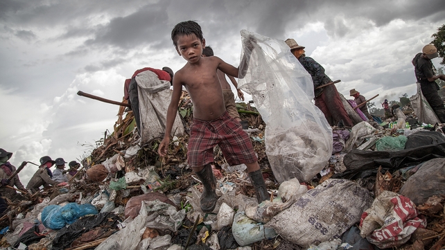 A young scavenger boy grabs plastic between tons of rubbish in the Anlong Pi in Siem Reap, Cambodia. Dozens of children scour the dump every day