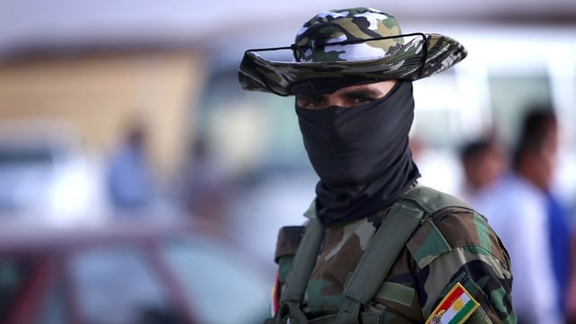An Iraqi Kurdish security guard waits to check the ID cards of families fleeing violence in the northern Nineveh province