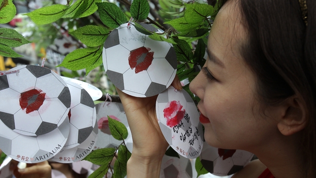 A South Korean woman kisses a paper football during an event to wish her country's team success in the World Cup
