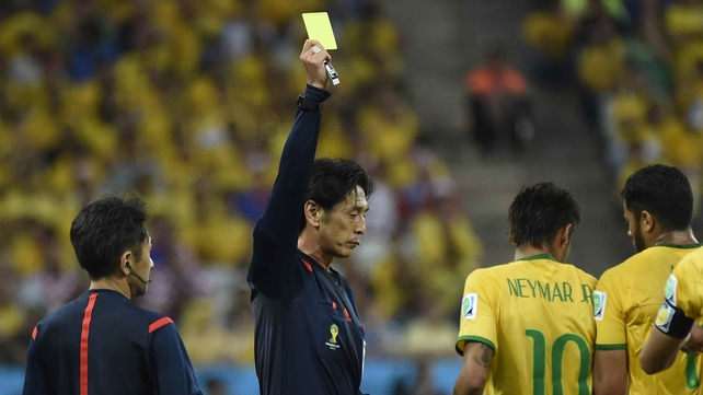 Head match referee Yuichi Nishimura hands Neymar a yellow card in the first half