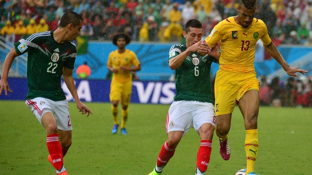 Mexico's Hector Herrera and Cameroon's Eric Maxim Choupo-Moting fight for the ball in rainy Natal