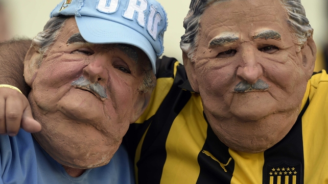 Fans wear masks of Uruguayan President Jose Mujica as they cheer prior to Uruguay vs Costa Rica