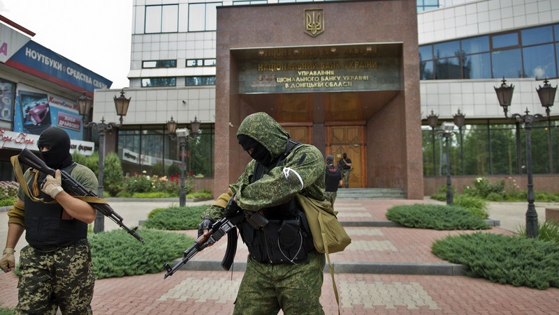 Pro-Russian forces stand guard outside a branch of the National Bank of Ukraine in Donetsk
