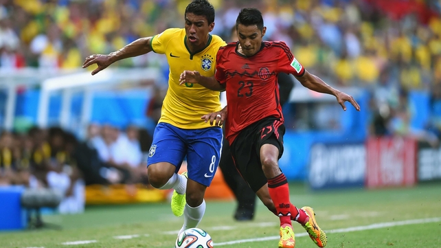 Brazil midfielder Paulinho and Mexico midfielder Jose Juan Vazquez compete side by side for the ball, during a scoreless opening half which saw great defensive efforts on both sides of the ball